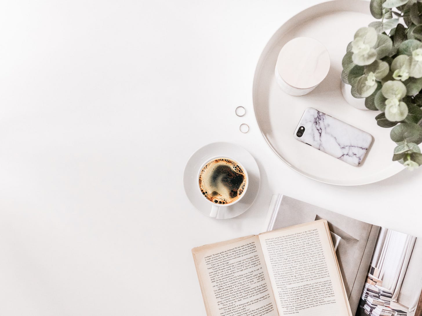 A table with a coffee, plant, phone, rings and books on the right A table with a coffee, plant, phone, rings and books on the right