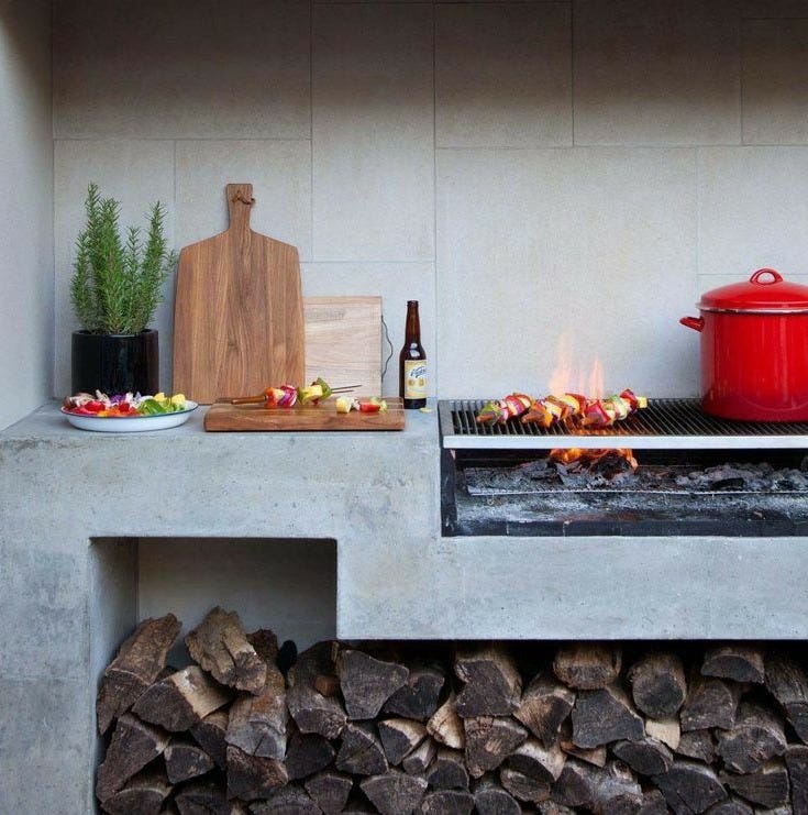 This may contain: an outdoor bbq with fire and food cooking on the grill, next to a pile of wood