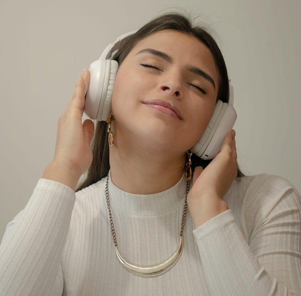 A woman with her eyes closed and a peaceful expression while listening to music — a visual of emotional ease and sonic self-care. A woman with her eyes closed and a peaceful expression while listening to music — a visual of emotional ease and sonic self-care.