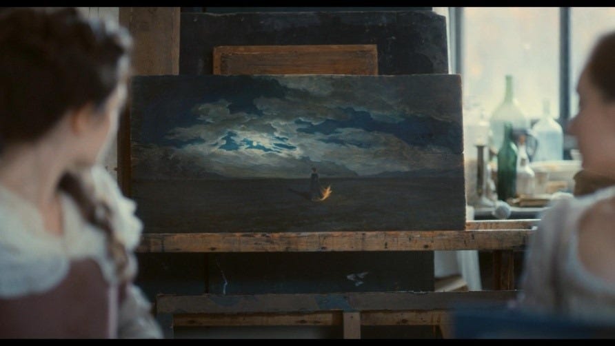 A imagem mostra uma cena escura com duas pessoas parcialmente visíveis nas laterais. O foco central é uma pintura em um cavalete. A pintura apresenta um céu noturno ou tempestuoso, com nuvens escuras e algumas formações mais claras e azuladas no centro. Há uma silhueta feminina, usando um vestido cuja barra está em chamas, próximo à parte inferior central da pintura. O ambiente parece ser um estúdio ou oficina, com outros objetos e equipamentos visíveis ao fundo.
