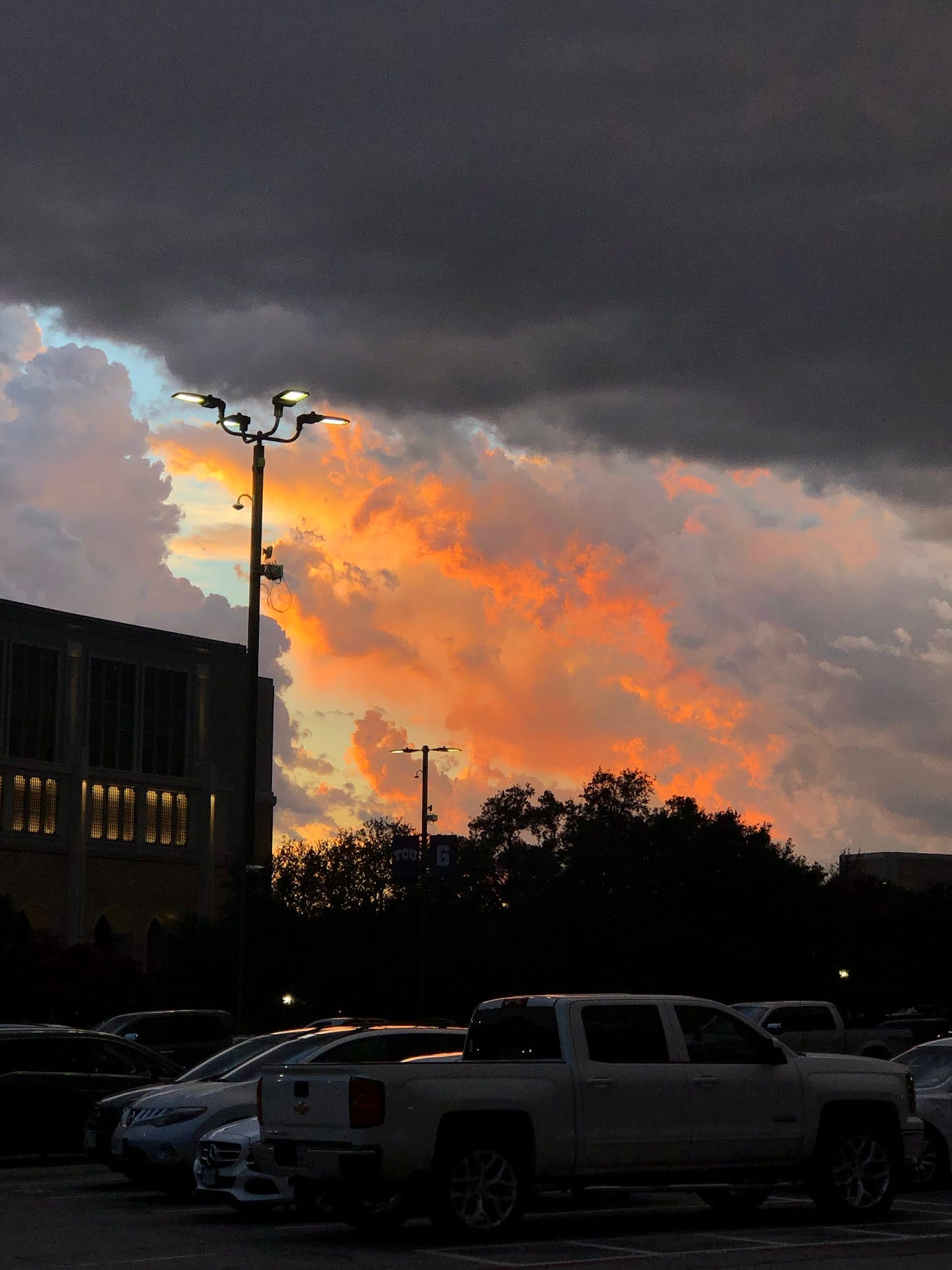 a photo of orange clouds with soft purple tints. The top of the photo is framed by a grey cloud.