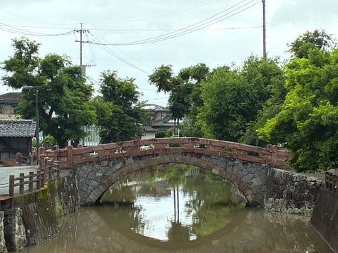 Photos of a pink and grey stone arch bridge over a dull green-brown waterway, overhung with trees