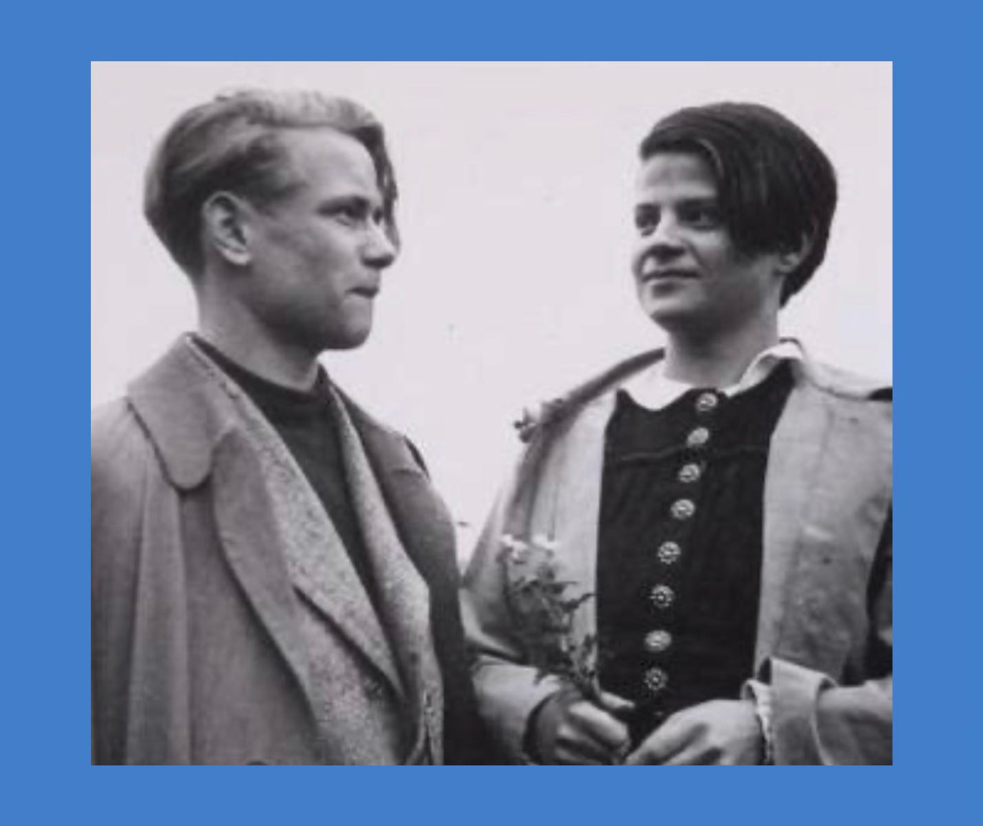 Black and white photo of a blonde teenaged boy and a brunette teenaged girl. They look relaxed and happy together. The girl is holding a sprig of wildflowers. Black and white photo of a blonde teenaged boy and a brunette teenaged girl. They look relaxed and happy together. The girl is holding a sprig of wildflowers.