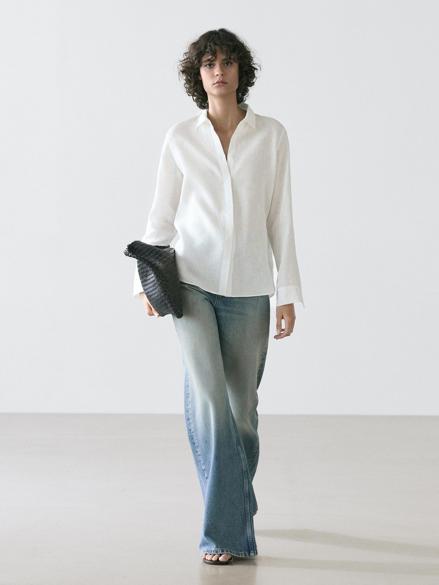 Flowy long-sleeved white shirt and light blue flared jeans set.