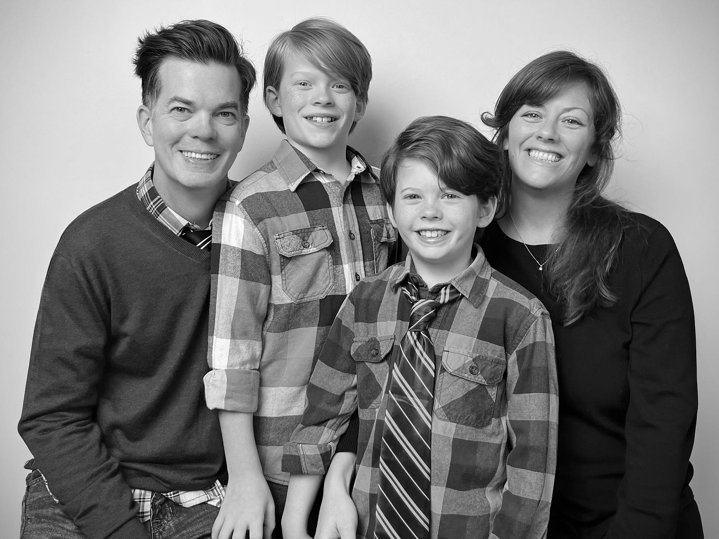 a black and white photo of a mom, dad and two younger sons