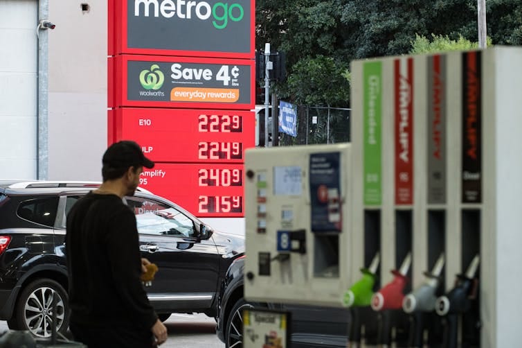 A man in a black cap and top walks through petrol station. A man in a black cap and top walks through petrol station.