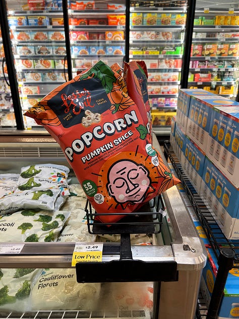 A grid of six photos of pumpkin-flavored products on shelves at an American Whole Foods: pumpkin spice grain-free cereal, pumpkin spice popcorn, pumpkin spice oat milk, cans of pumpkin chai hard tea, pumpkin spice oat bites and a pumpkin almond flour pancake mix.