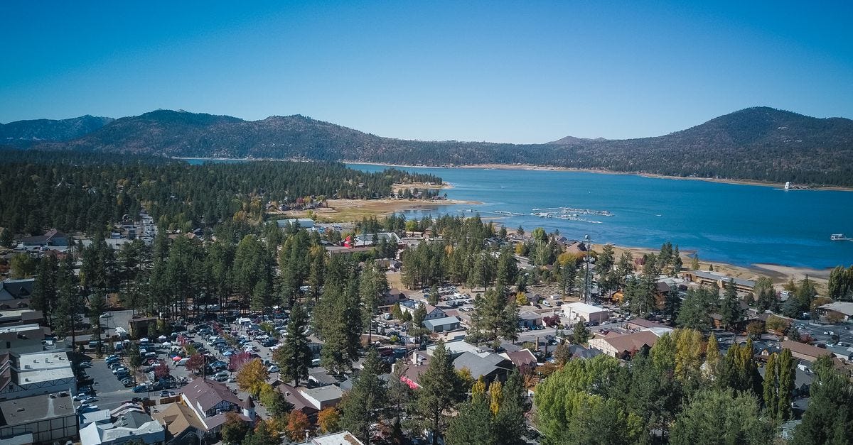Photo: Kindel Media / Pexels A serene aerial view of a town by a lake surrounded by mountains and nature.