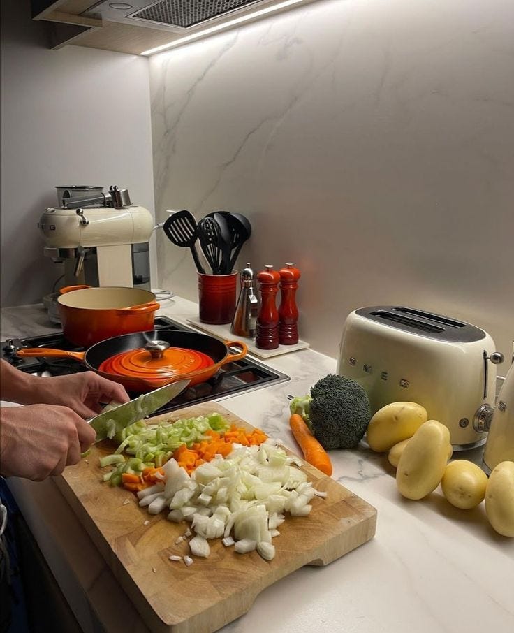 This may contain: a person chopping vegetables on a cutting board in a kitchen next to a toaster