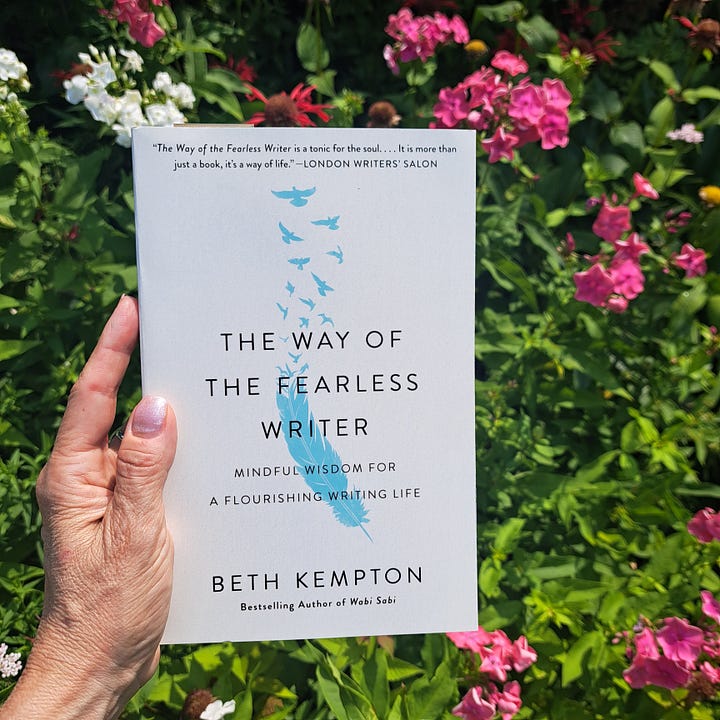 hand in a garden holding The Way of the Fearless Writer, and The Soul's Code book on a wooden tablebook covers