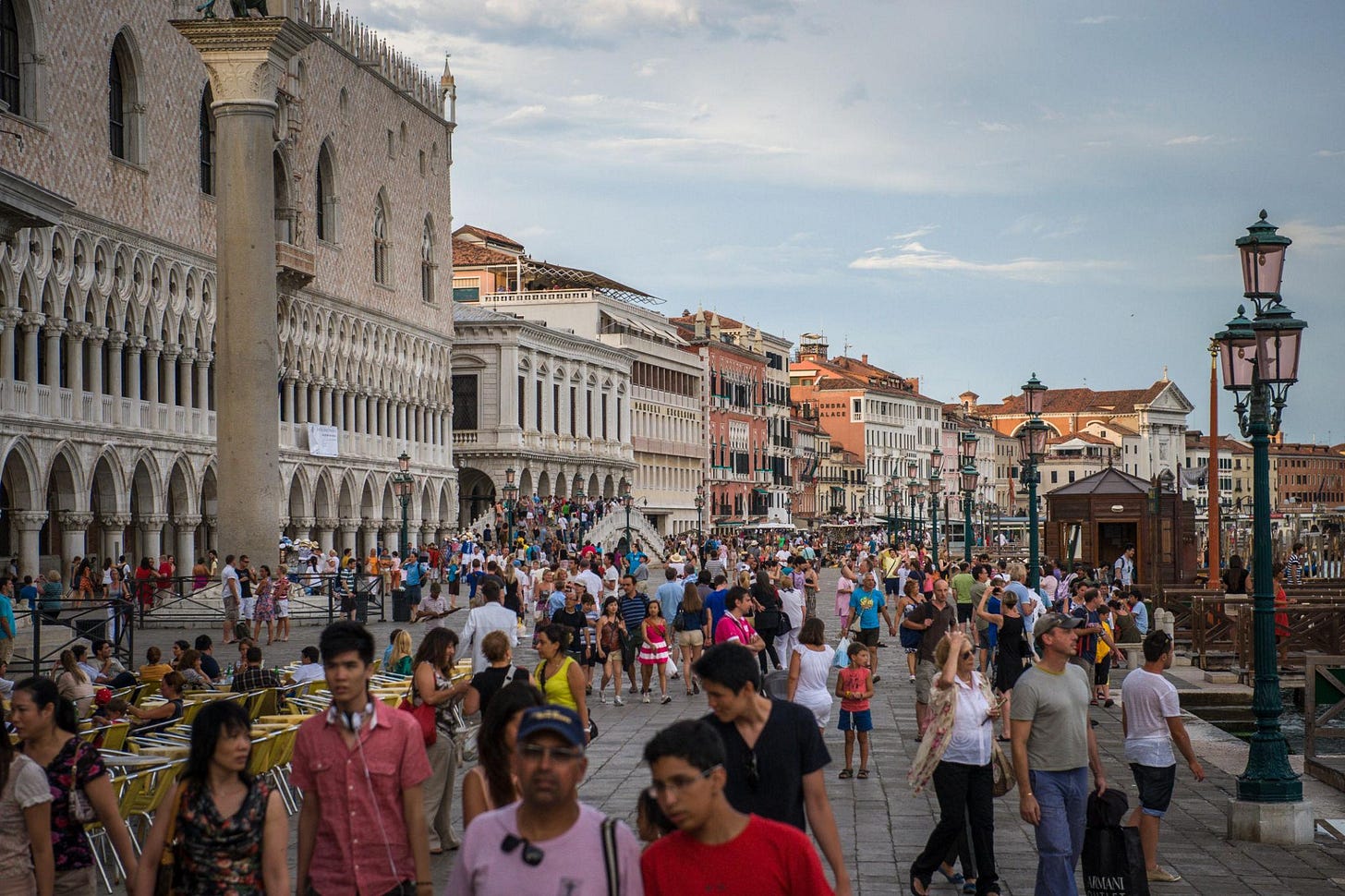 Large summer crowds fill the walkway next to the Grand Canal in Venice, Italy