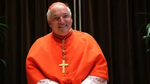 Franco Origlia/Getty Images Jean-Marc Aveline poses in a red top with a gold cross