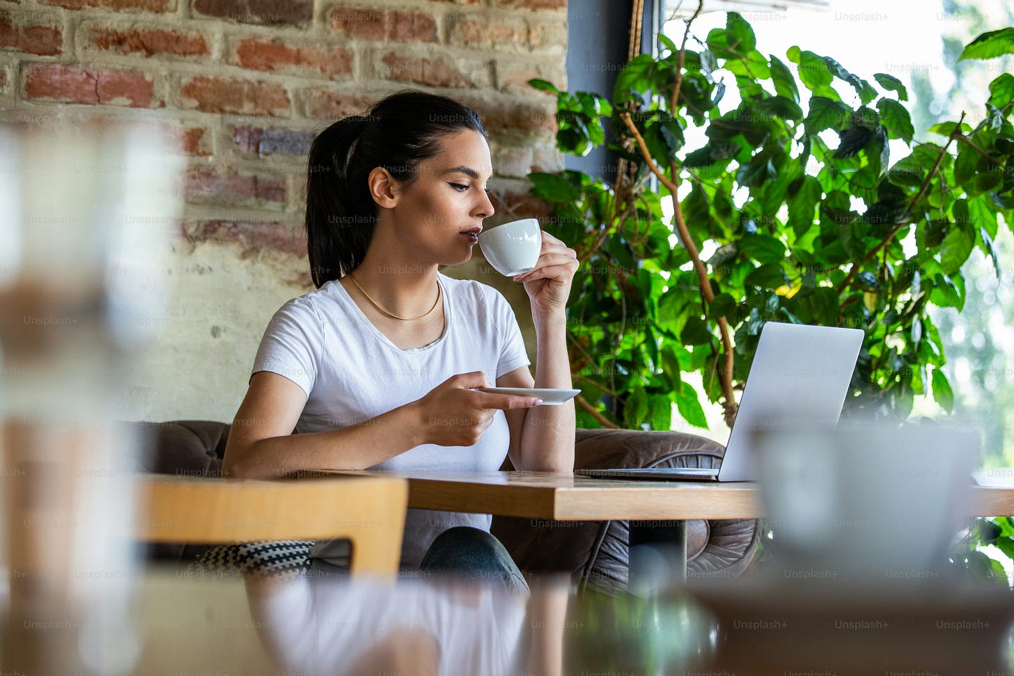 Woman in a good mood with cup of coffee sitting in cafe. Bright sunny morning. Gorgeous female drinking coffee and surfing the net in the coffee break. Morning coffee is my daily Woman in a good mood with cup of coffee sitting in cafe. Bright sunny morning. Gorgeous female drinking coffee and surfing the net in the coffee break. Morning coffee is my daily