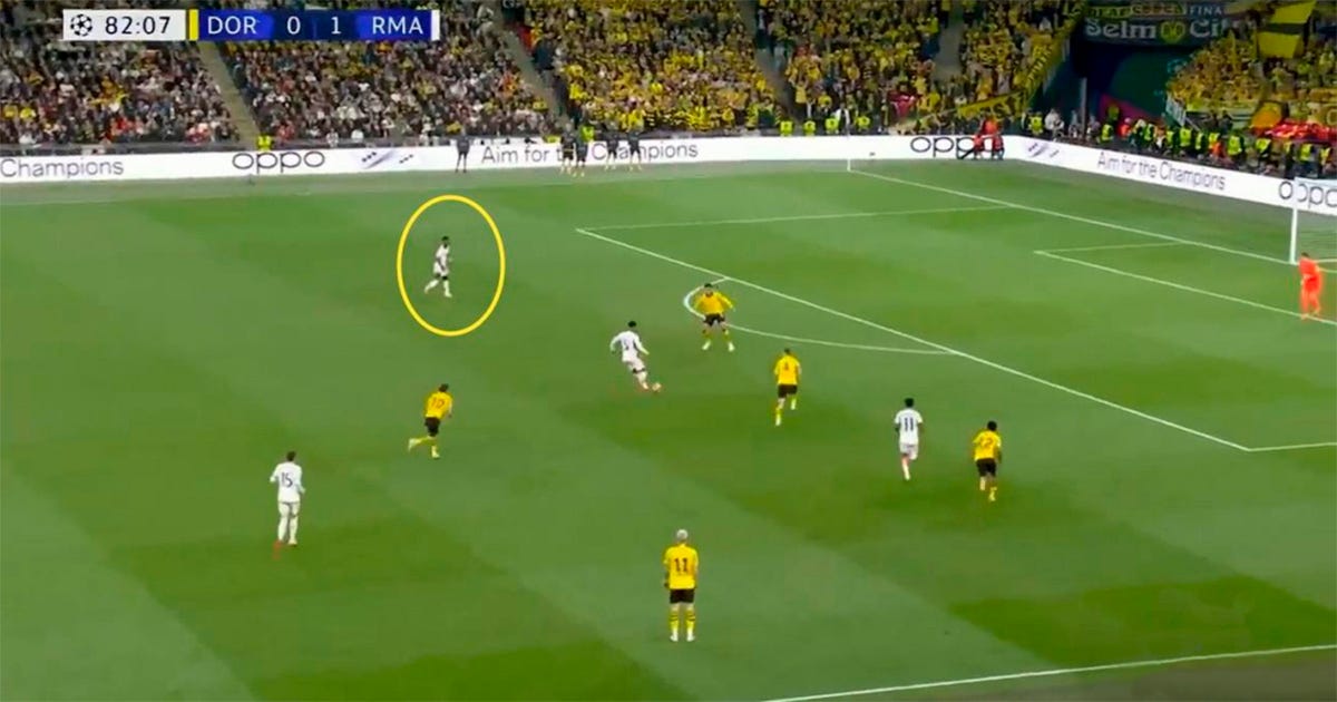 Quadro de partida de futebol entre Borussia Dortmund e Real Madrid transmitida pela emissora SBT mostra campo com cinco jogadores de uniforme amarelo e preto marcando outros cinco atletas vestidos de branco. Ao fundo, arquibancadas lotadas predominam em tons de amarelo. Quadro de partida de futebol entre Borussia Dortmund e Real Madrid transmitida pela emissora SBT mostra campo com cinco jogadores de uniforme amarelo e preto marcando outros cinco atletas vestidos de branco. Ao fundo, arquibancadas lotadas predominam em tons de amarelo.