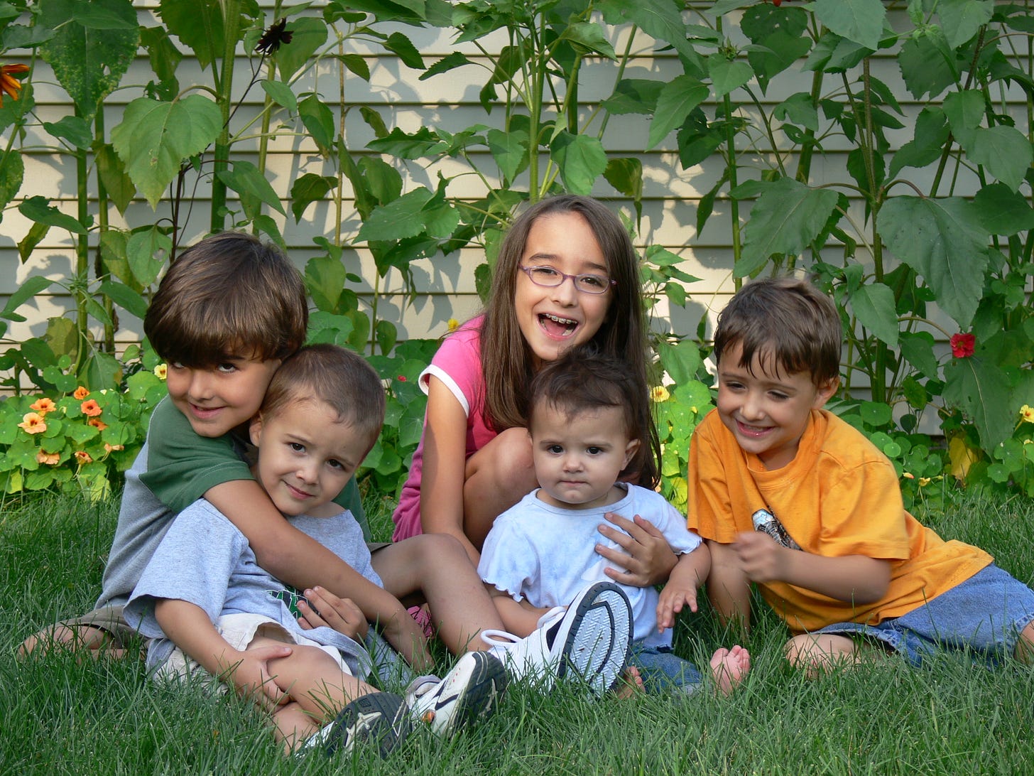 kids posing in front of sunflowers and nasturtiums