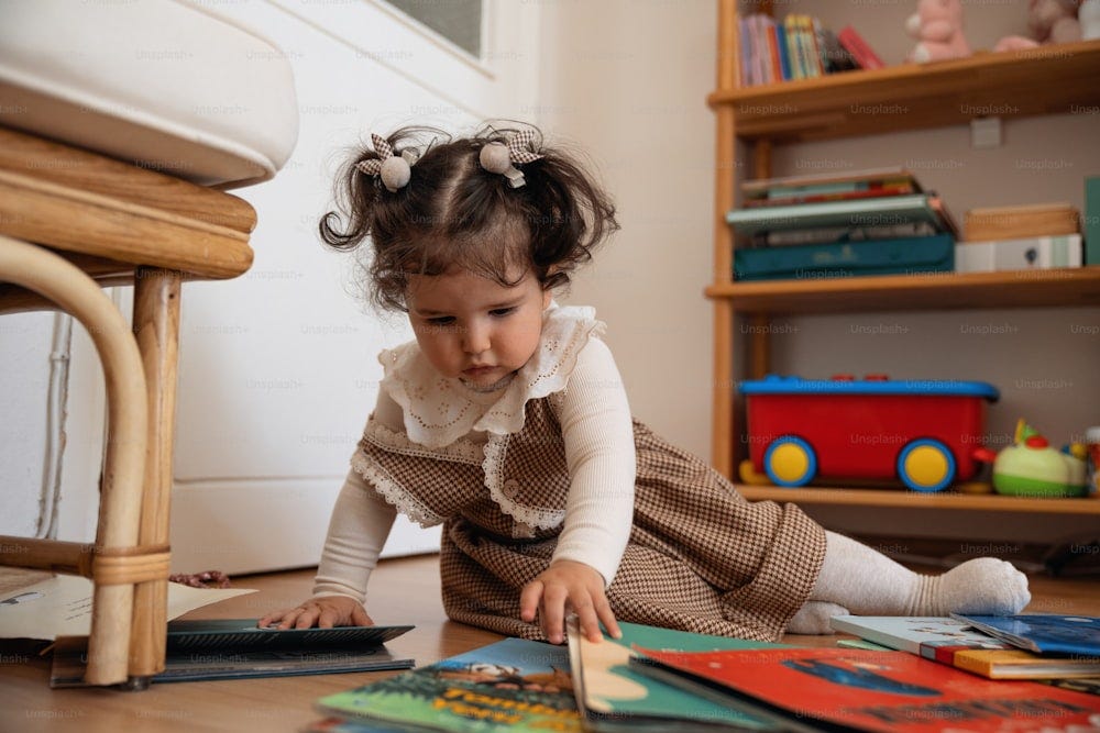 A little girl is playing with books on the floor