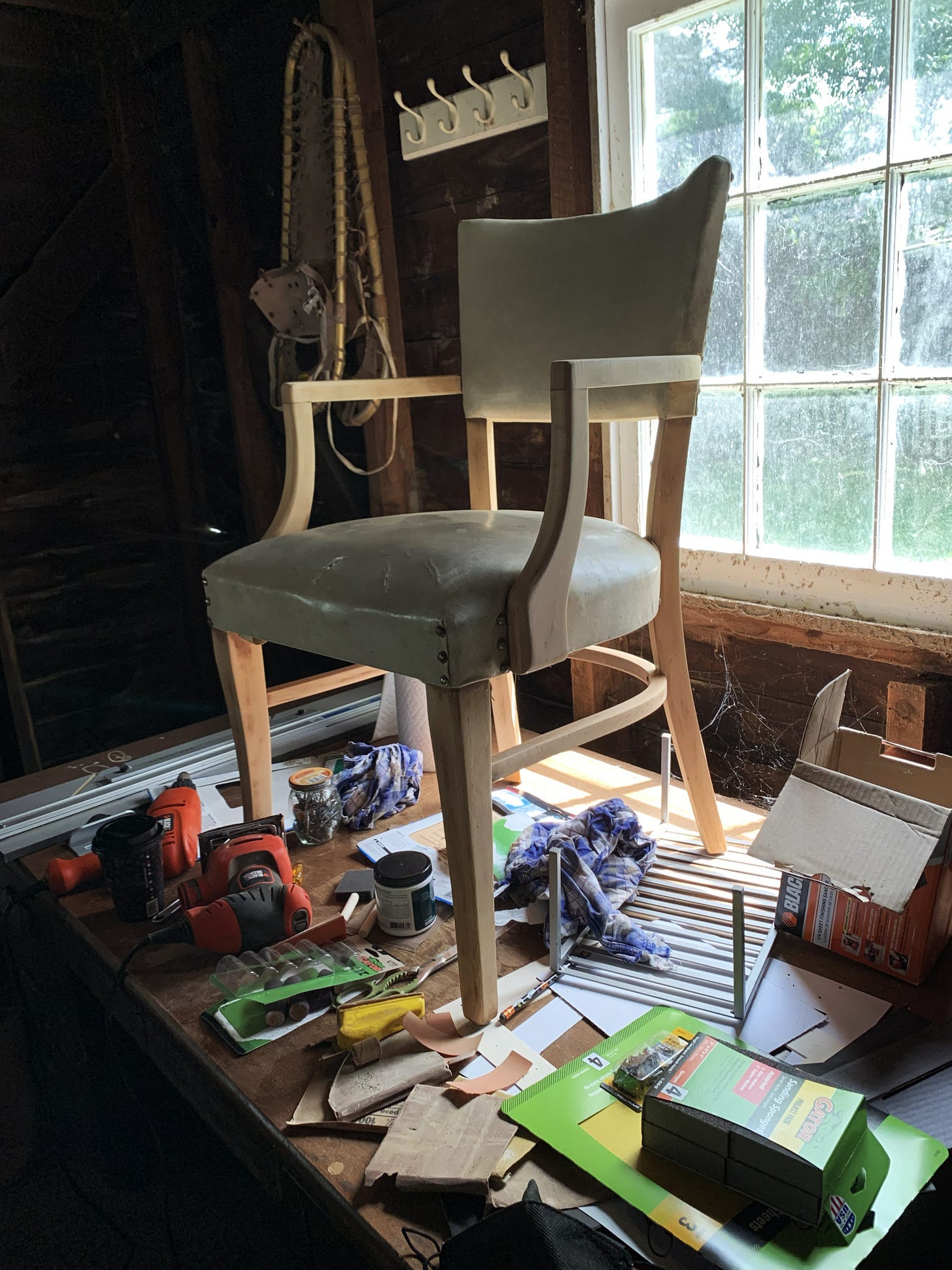 A color photograph of a dining room chair on a table in a garage workshop space