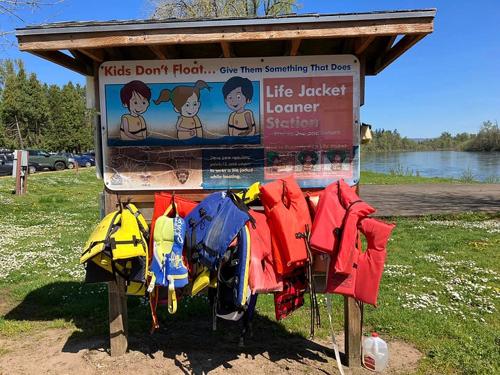 Life jackets, paddler wearing life jacket, backpack, water bottles, picnic basket, and outdoor shoes