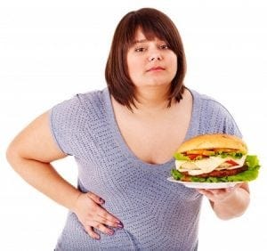 a fat girl holding a plate of food and holding her side in pain