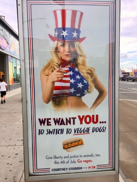Bus stop Peta ad with woman in red, white and blue outfit pointing at viewer with caption "I want you to switch to veggie dogs"