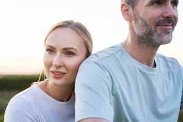 Caucasian middle aged couple standing behind each other outdoors in the summer Caucasian middle aged couple standing behind each other outdoors in the summer emotional safety stock pictures, royalty-free photos & images