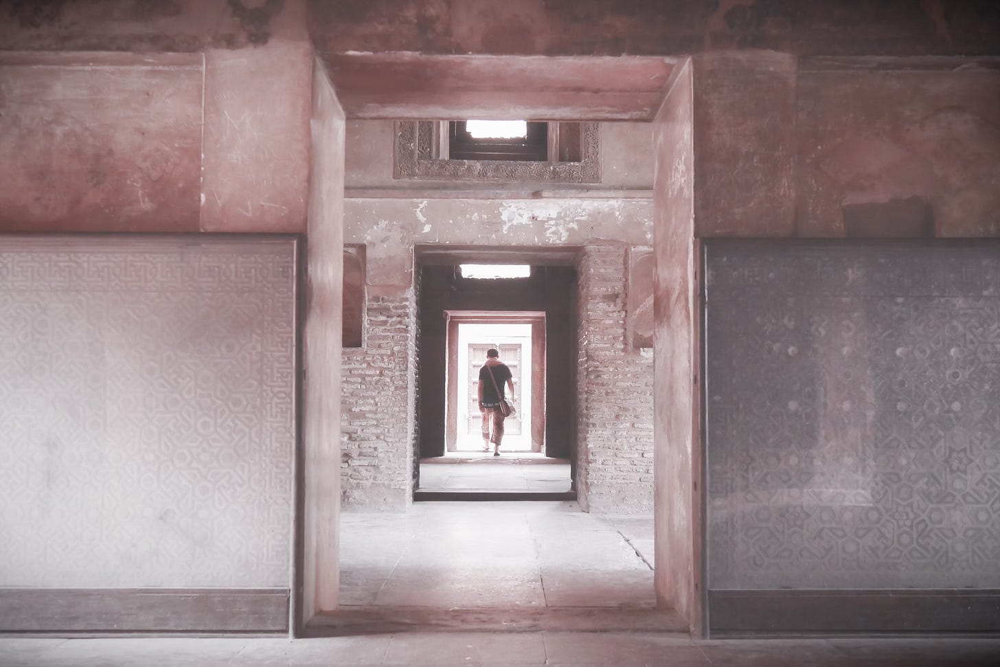 man walking through an ancient temple with many doorways