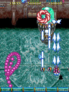 A screenshot showing the boss fight from stage 3 against a jellyfish-looking ship, which has fired off a shifting, squirming segment of attached purple orbs, which float around in an ever-shifting form you need to avoid. A screenshot showing the boss fight from stage 3 against a jellyfish-looking ship, which has fired off a shifting, squirming segment of attached purple orbs, which float around in an ever-shifting form you need to avoid.
