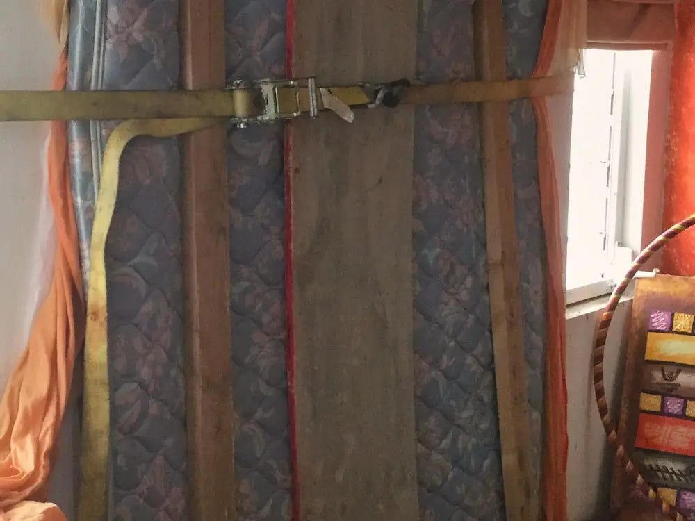 A mattress is strapped against a window a patio door