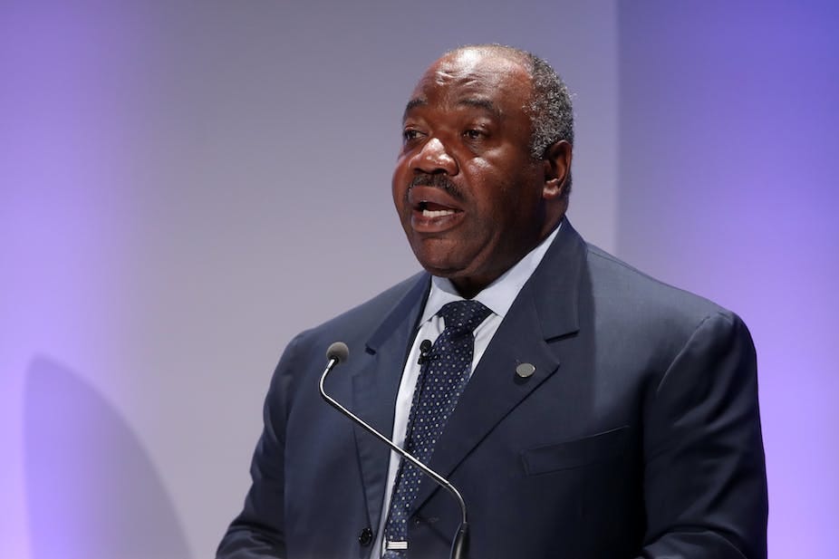Man in a grey suit and tie speaking into a microphone Man in a grey suit and tie speaking into a microphone