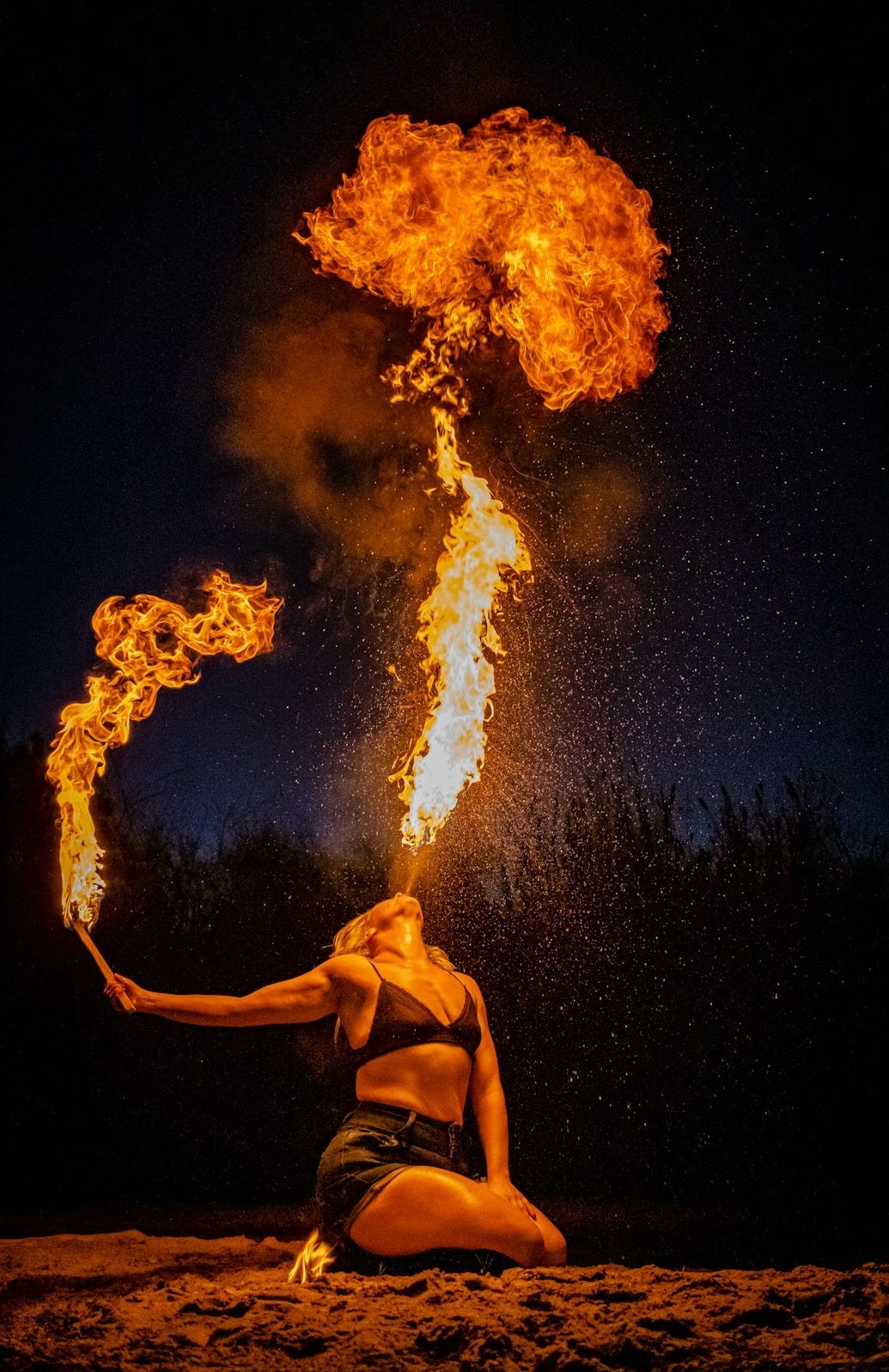 man in black shorts standing in front of fire