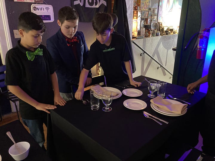 Left: Mohammad Niazi, Lincoln Pretz, and Landon Cascio-McClelland set the table for their lunch at Katora Coffee in downtown Fredericksburg. Right, the Boys in Bowties talk with club leader Tony Wishard, an assistant principal at Hugh Mercer Elementary.
