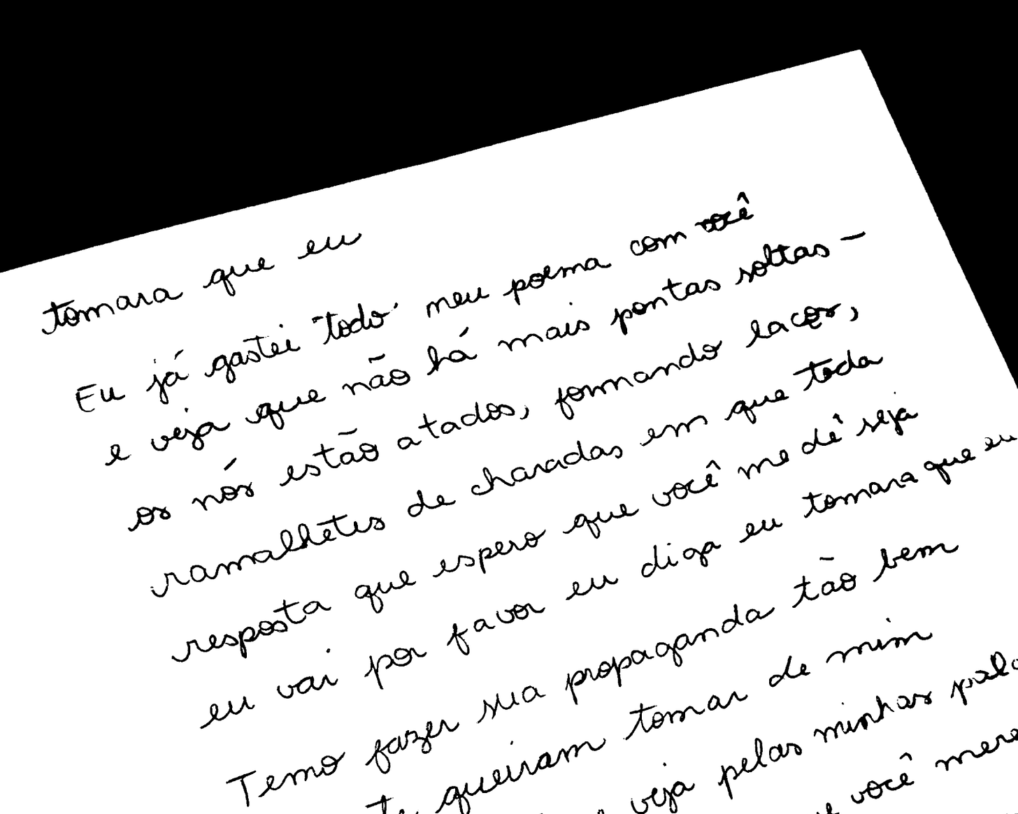 Página de caderno com texto manuscrito: poema "Tomara que eu". "Eu já gastei todo meu poema com você e veja que não há mais pontas soltas - os nós estão atados, formando laços, ramalhetes de charadas em que toda resposta que espero que você me dê seja eu vai por favor eu diga eu tomara que eu."