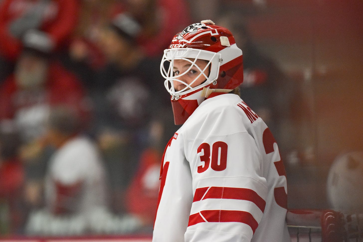 Wisconsin women's hockey goaltender Ava McNaughton looking to the side standing in net Wisconsin women's hockey goaltender Ava McNaughton looking to the side standing in net