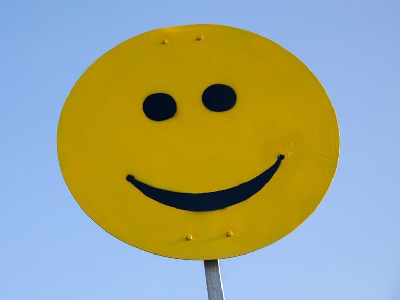 a yellow smiley face sign with a blue sky in the background