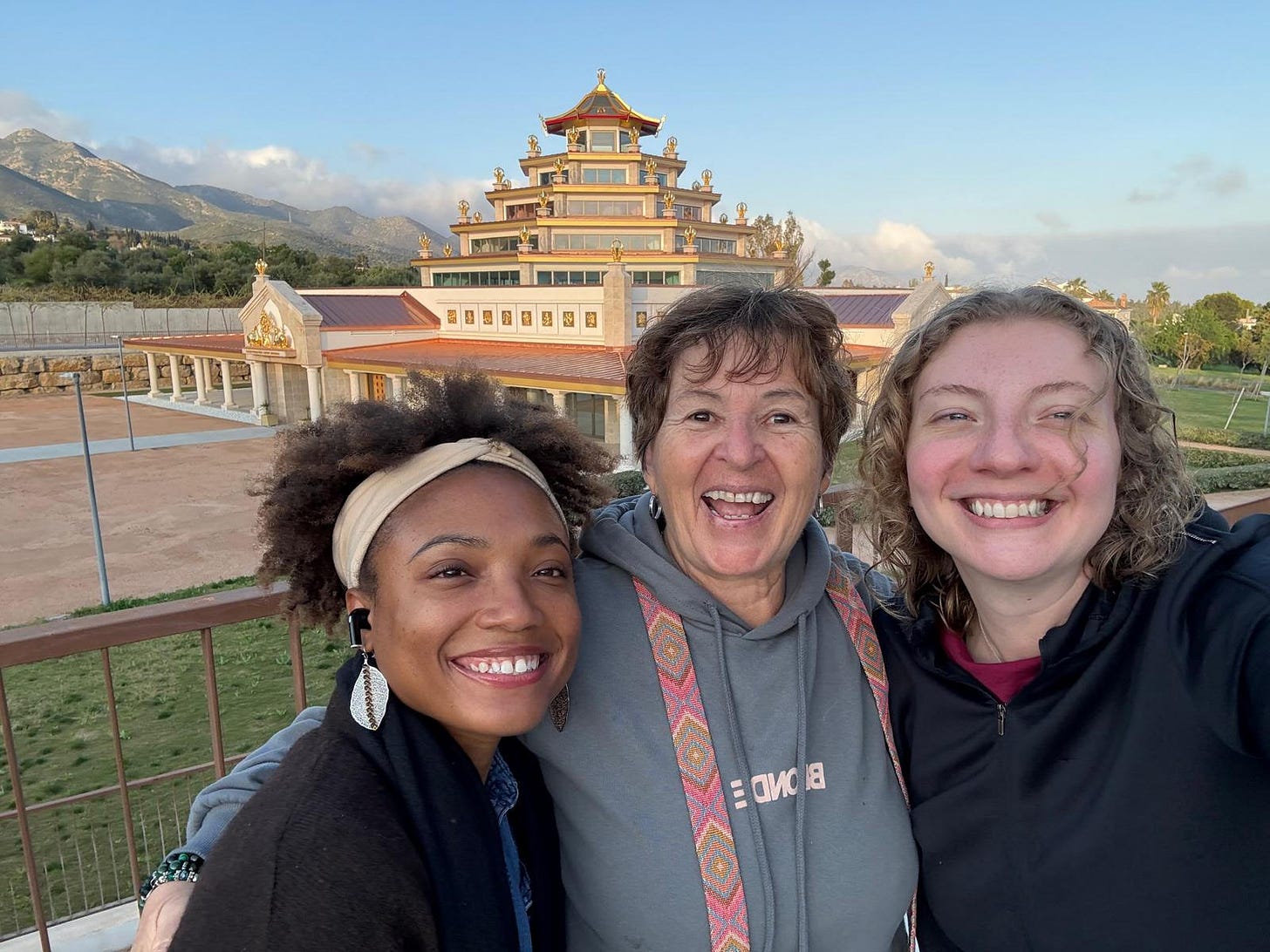 Three women smiling together on a balcony with the golden Buddhist temple and mountain range glowing behind them at sunset. Three women smiling together on a balcony with the golden Buddhist temple and mountain range glowing behind them at sunset.