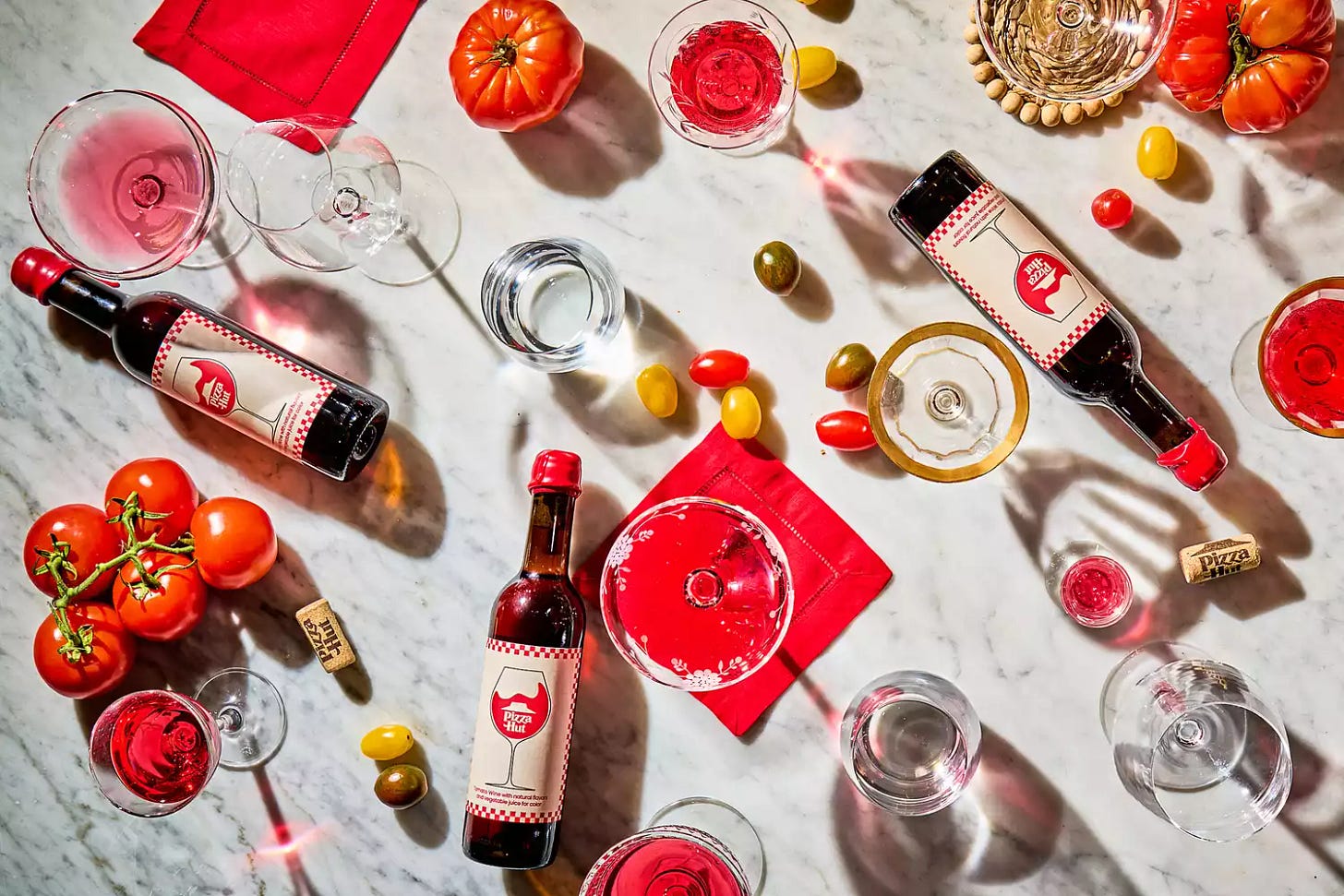 Pizza Hut's tomato wine, wine glasses, red napkins and tomatoes on a marble surface. 