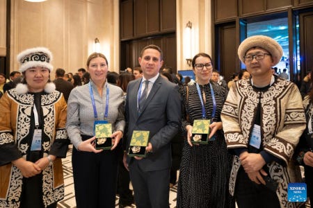 Des maires montrent des médailles qui leur ont été remises par la ville de Harbine, entre deux Chinois en tenues polaires traditionnelles.