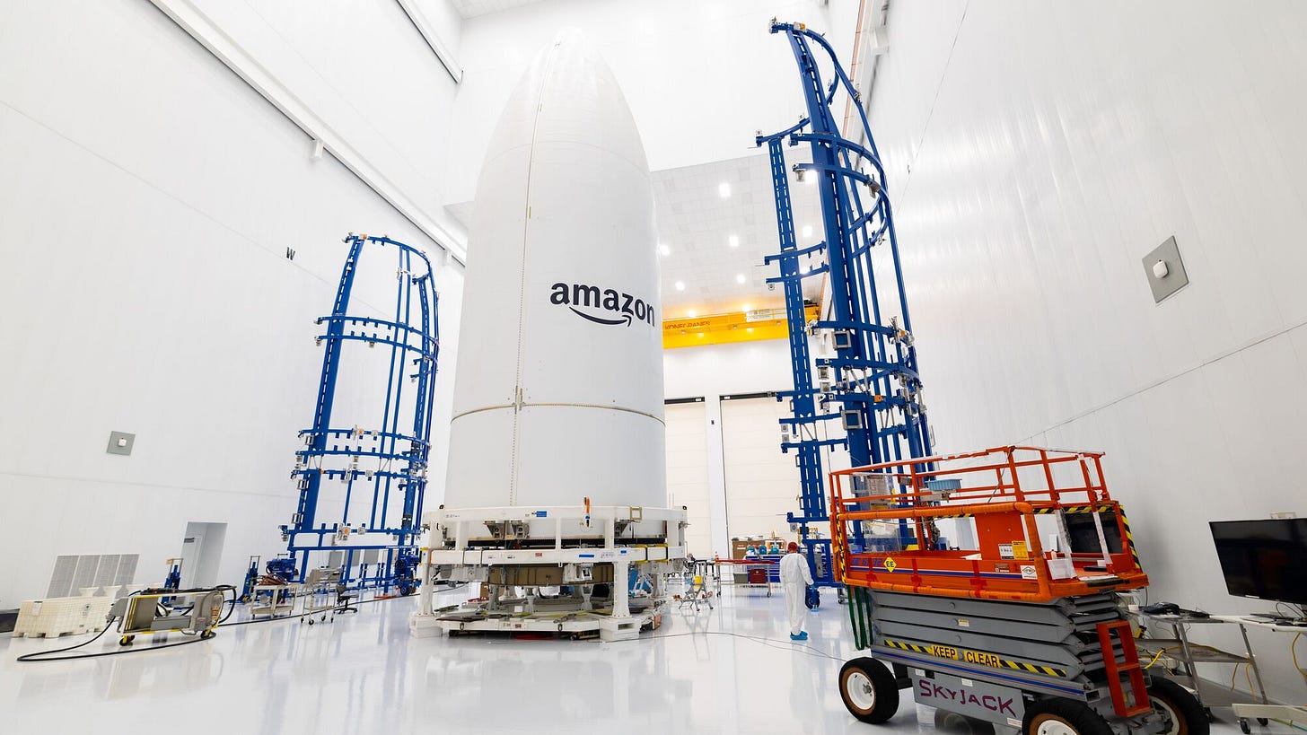 Rocket body with Amazon branding in preparation facility with blue scaffolding and orange lift