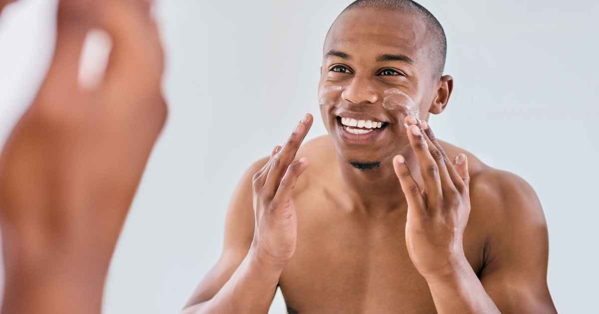 man applying moisturizer to his face in the bathroom 