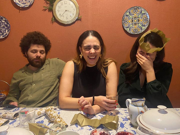 A male and two females sit behind a table with Christmas crackers on