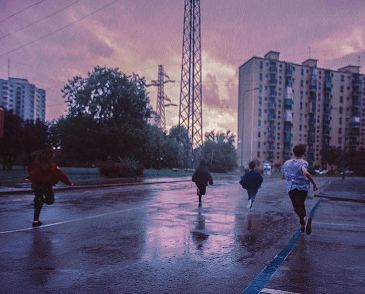 This may contain: some people are walking down the street in the rain