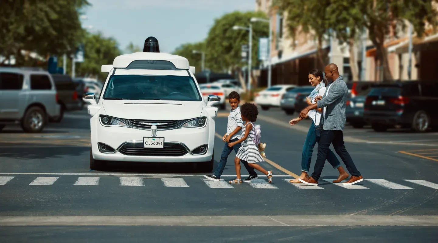 Una camioneta Chrysler Pacifica Hybrid de Waymo completamente autónoma en un cruce peatonal.