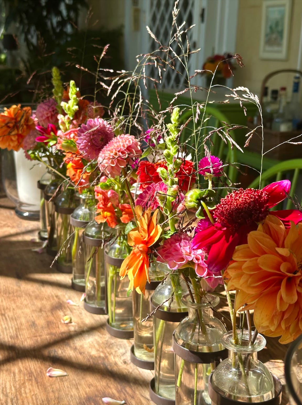 pretty brightly coloured flowers in vases along a dining table