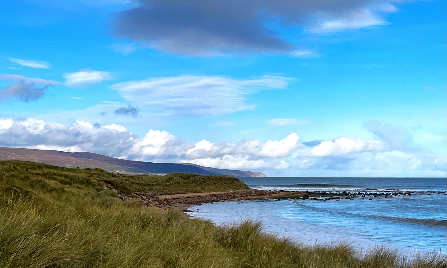 dramatic cloudscape above the sea with weathered hills in the distance