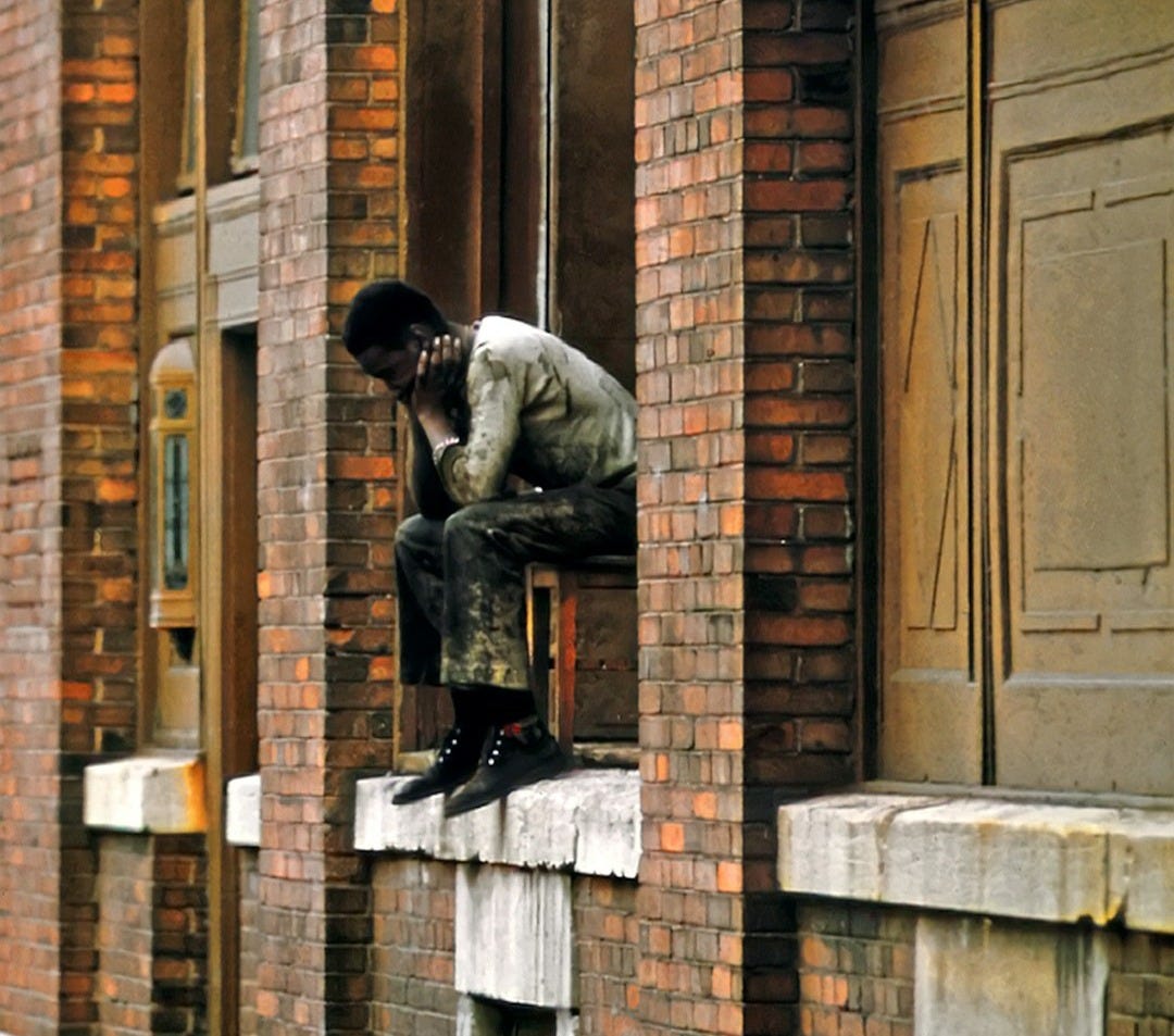 a man sitting on the ledge of a building a man sitting on the ledge of a building