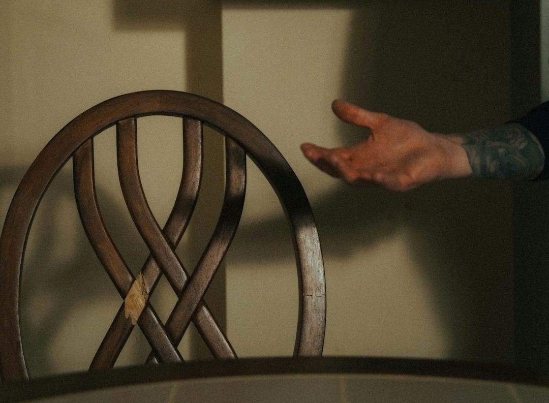 person in blue denim jeans standing near brown wooden chair