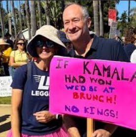 Older white couple holding pink protest sign which reads "If Kamala was president, we'd be at brunch! No Kings!"