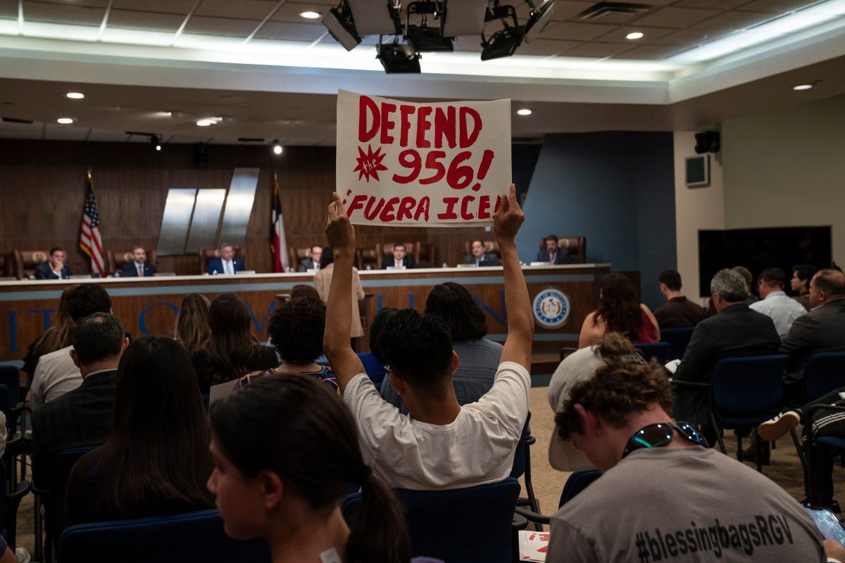 A person holds up a sign in opposition to building an immigration detention center in McAllen during a city commissioners meeting in McAllen on April 13, 2026.