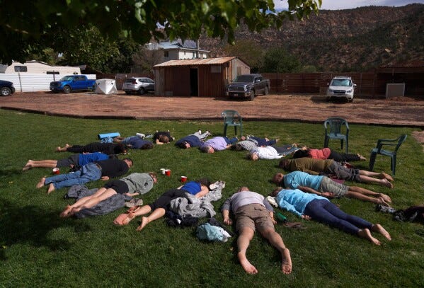 Participants lay face down on the grass during an integration circle at an ayahuasca retreat in Hildale, Utah, Oct. 15, 2022. (AP Photo/Jessie Wardarski, File)