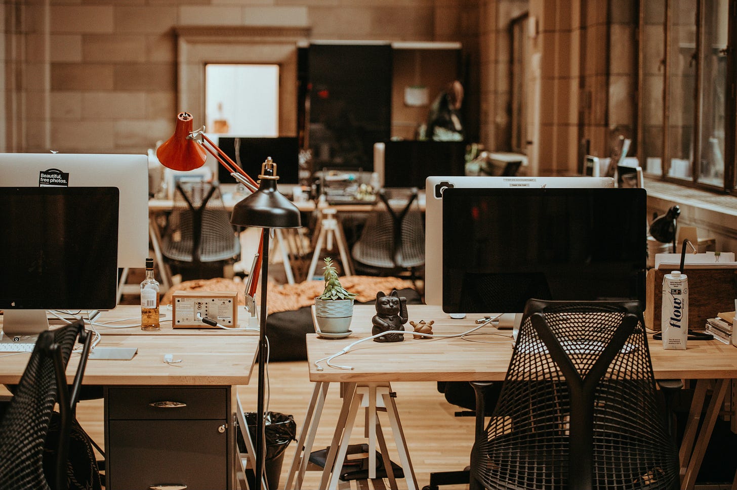 Open workspace with desks, monitors, lamps, and decor.